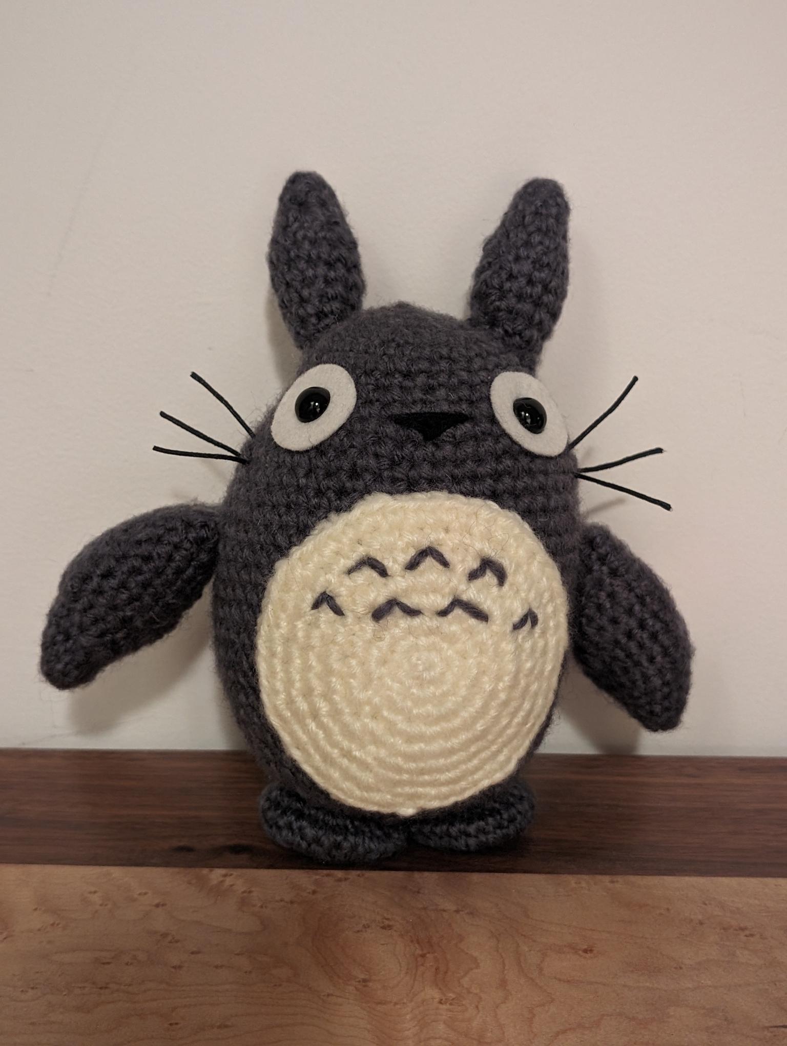completed Totoro amigurumi standing on a wooden dresser in front of a white wall