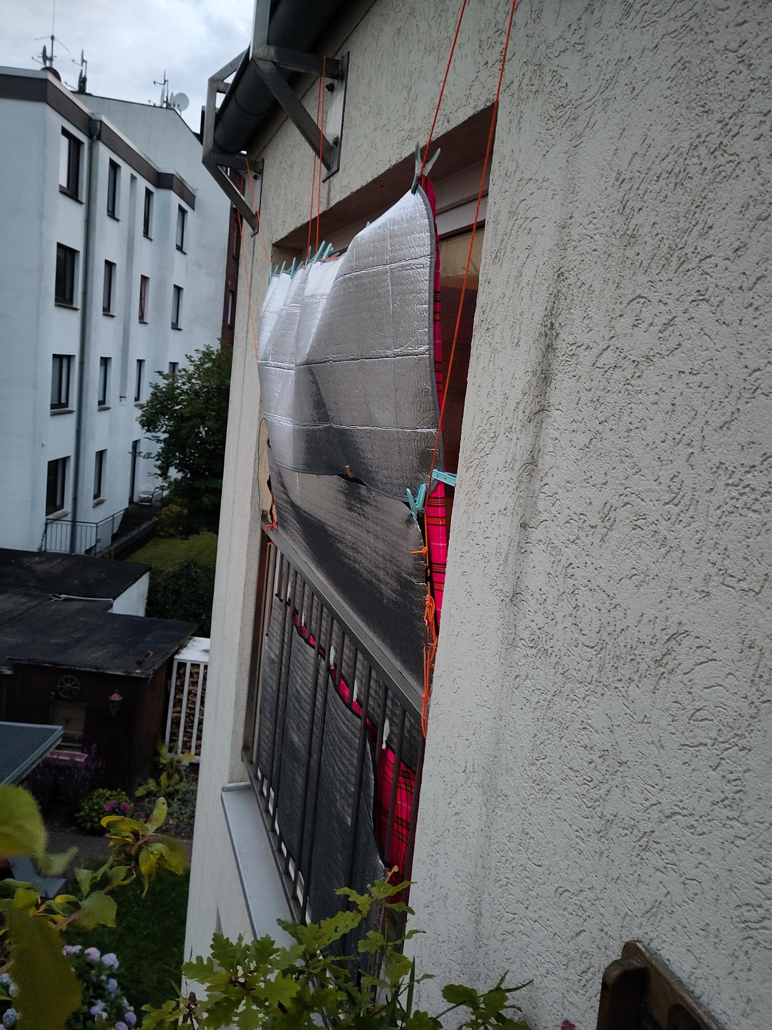 Mylar insulated sheets attached horizontally to Paracord and fabric outside a large French balcony