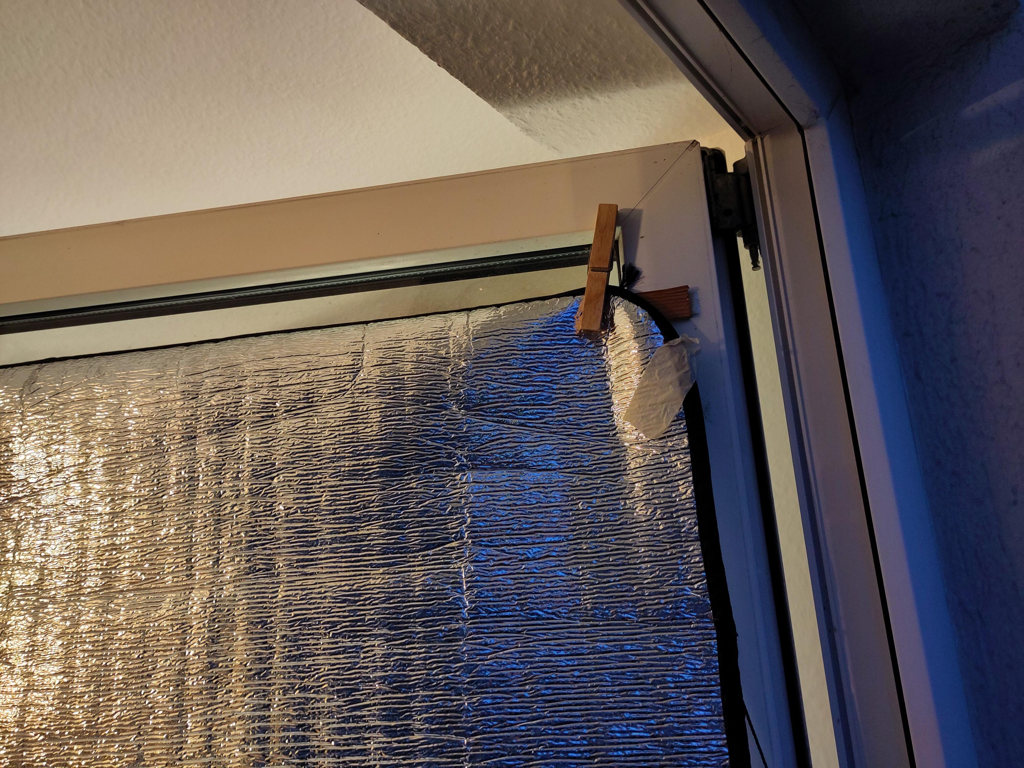 Detail of the balcony windows: there is a thin (4mmx20mm) wooden board taped to the window frame with removable double sided 3m tape. The reflective mat is attracted to the rail with a clothespin.