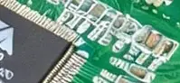 Another crop showing the edge of a QFN chip and more resistors and decoupling capacitors. The pins are at weird angles and don't line up with the pads or traces. The small components looks like outlined blobs and the silkscreen designation have become squiggles.