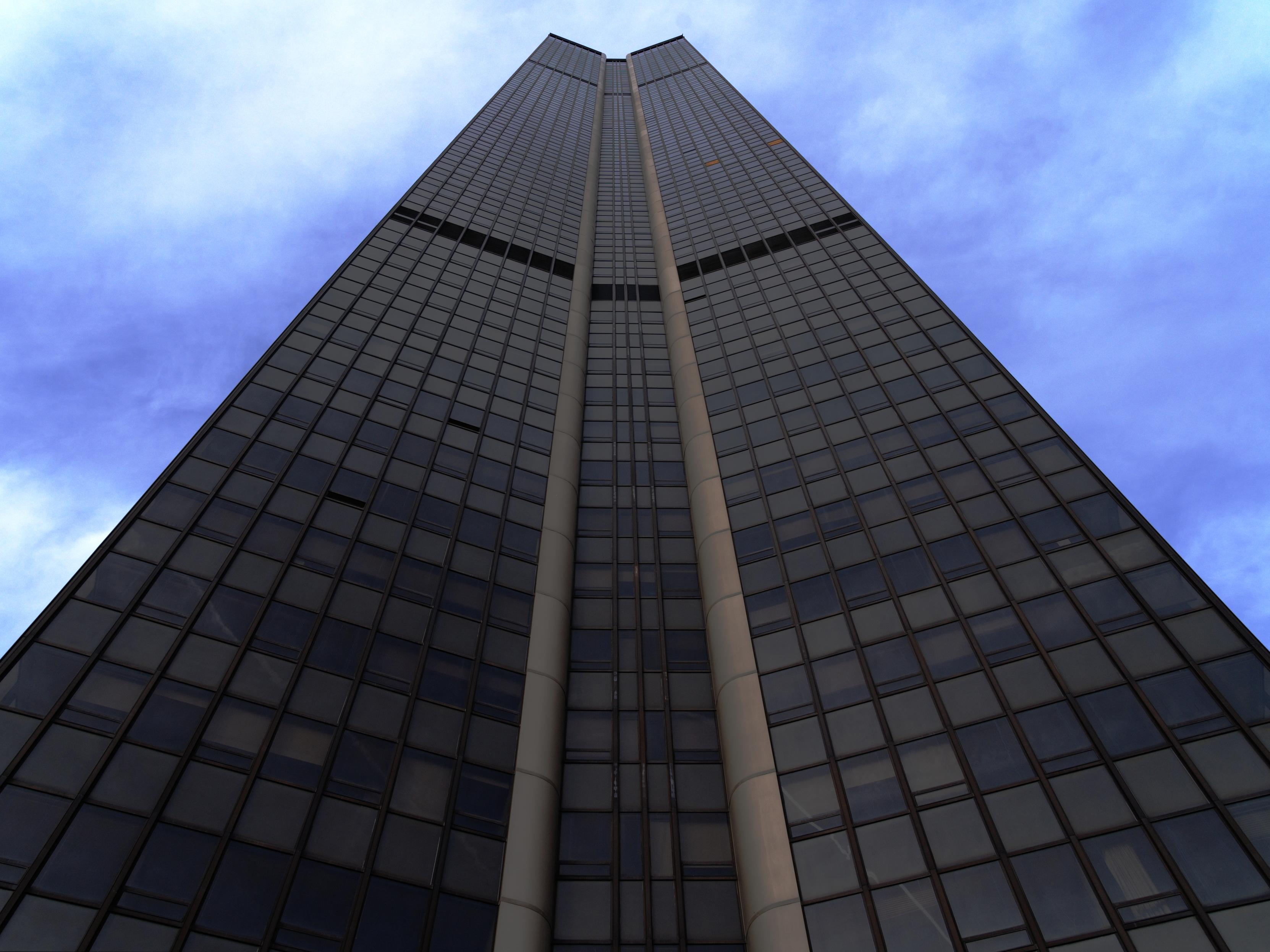Photo of a skyscraper from the bottom. The building fills nearly the whole image. The wedges of sky on either side are blue, marbled with clouds.