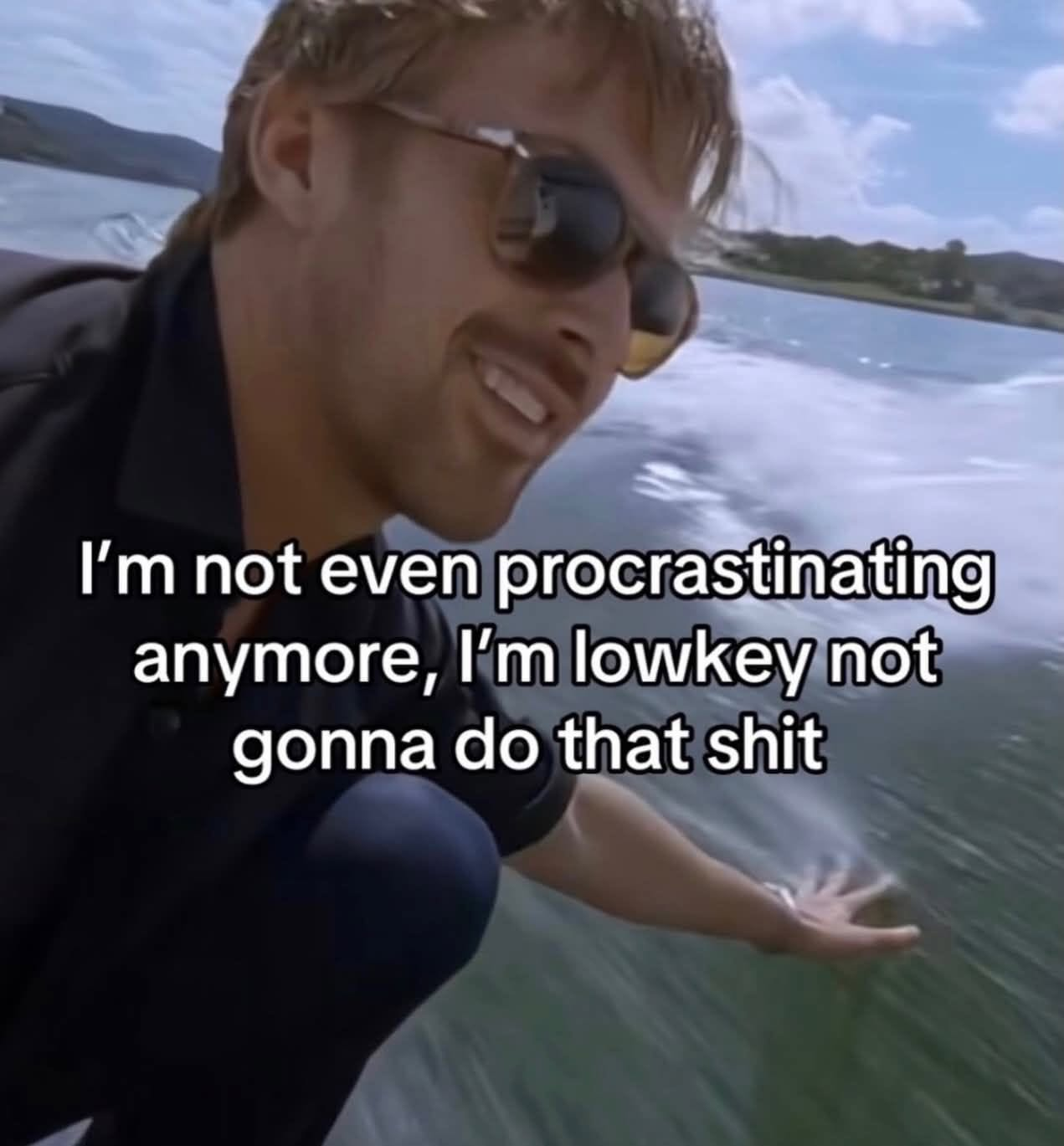 an image of Ryan Gosling wearing sunglasses leaning over the side of a moving boat and reaching out to touch the water, the caption text reads: "I'm not even procrastinating anymore, I'm lowkey not gonna do that shit"