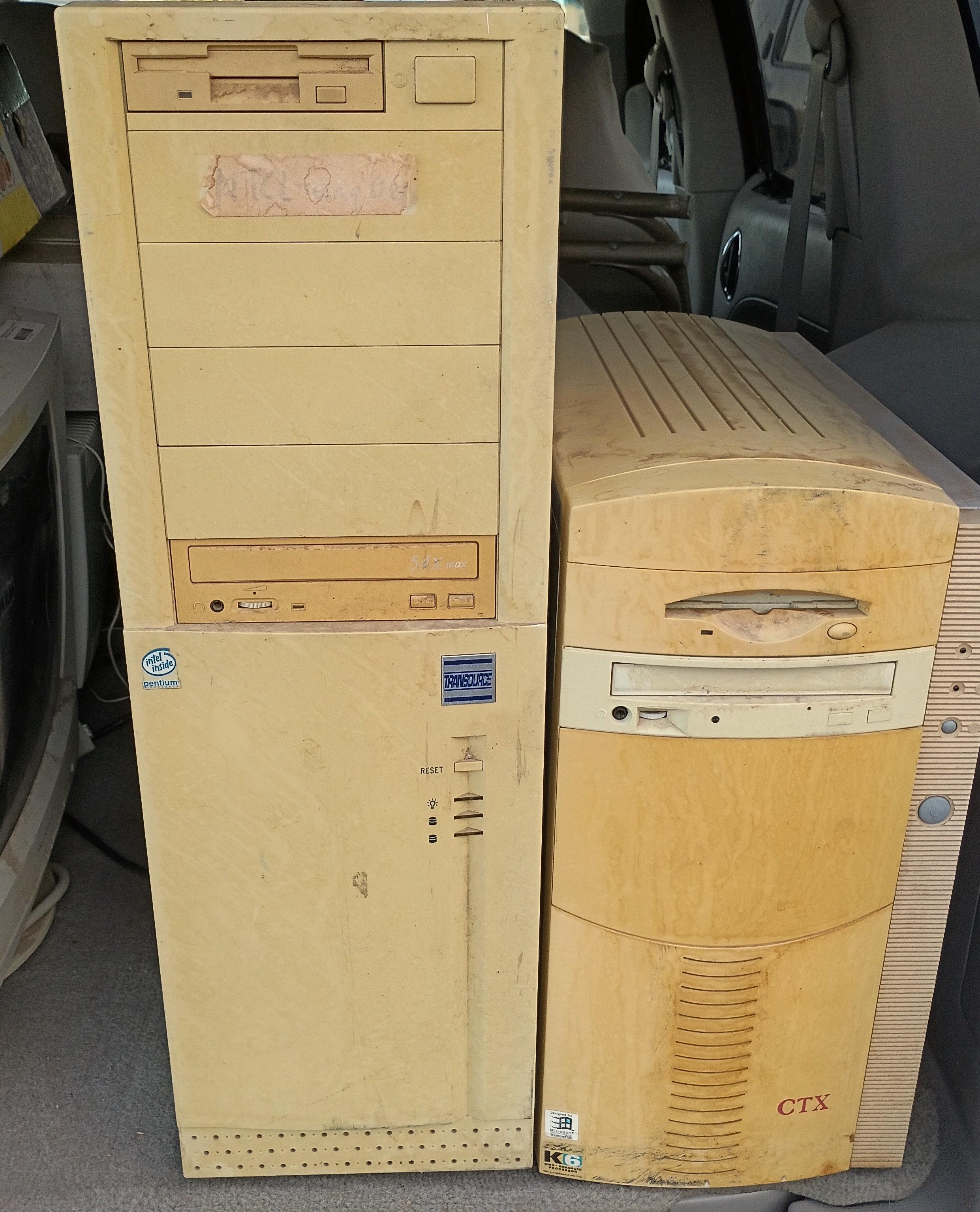 Two 20 year old beige tower PCs, covered in dust and dirt, in the back of a van.