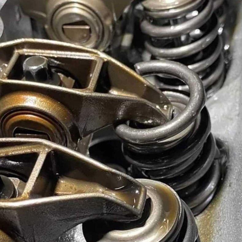 A view of two rocker arms, valves, and springs inside the header of a modern ICE engine. One of them is broken, with the plate at the top of the valve having been pushed past the top of the spring, meaning the valve is continuously open and likely has impacted against the piston - if this engine has ever run in this condition.