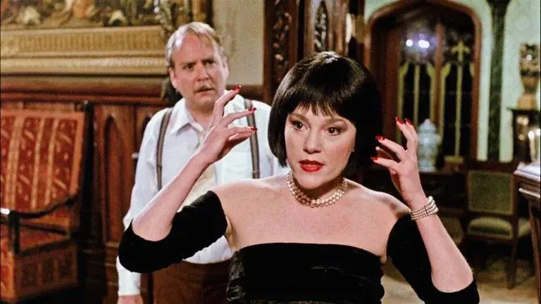 Catherine O'Hara in Clue miming flames on the side of her face