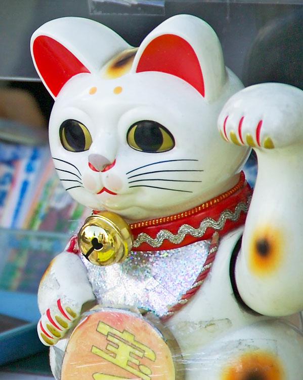 The maneki-neko (招き猫, lit. 'beckoning cat') is a common Japanese figurine which is often believed to bring good luck to the owner. In modern times, they are usually made of ceramic or plastic. The figurine depicts a cat, traditionally a calico Japanese Bobtail, with a paw raised in a beckoning gesture. The figurines are often displayed in shops, restaurants, pachinko parlors, dry cleaners, laundromats, bars, casinos, hotels, nightclubs, and other businesses, generally near the entrance, as well as households. Some maneki-neko are equipped with a mechanical paw that slowly moves back and forth.