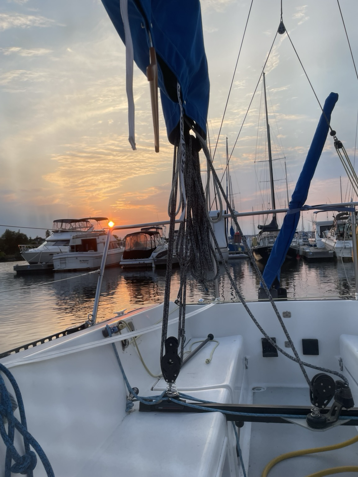 view off the back of my boat, with the sun setting over water. various other boats are around me.