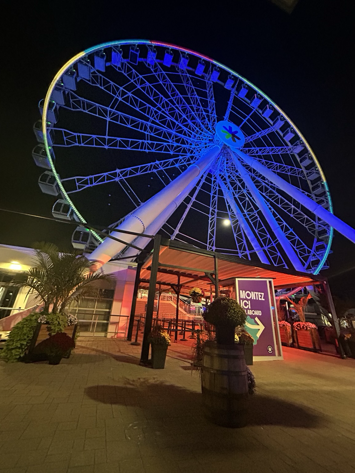 A view from below of la Grande Roue (big Ferris wheel) looming overhead at night, on the Montreal riverfront.