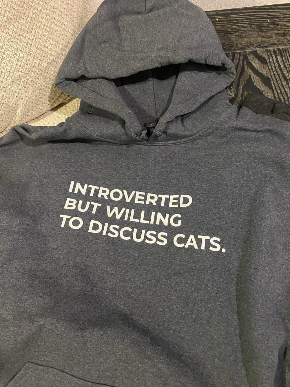 photo of a bkack hoodie with the words:

INTROVERTED 
BUT WILLING 
TO DISCUSS CAT.