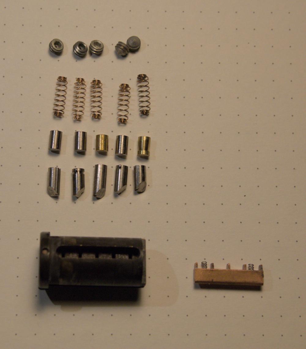 The whole lock, showing the rather corroded brass plug and a copper sidebar with two tiny springs. There are also hardened steel anti-drill pins installed.