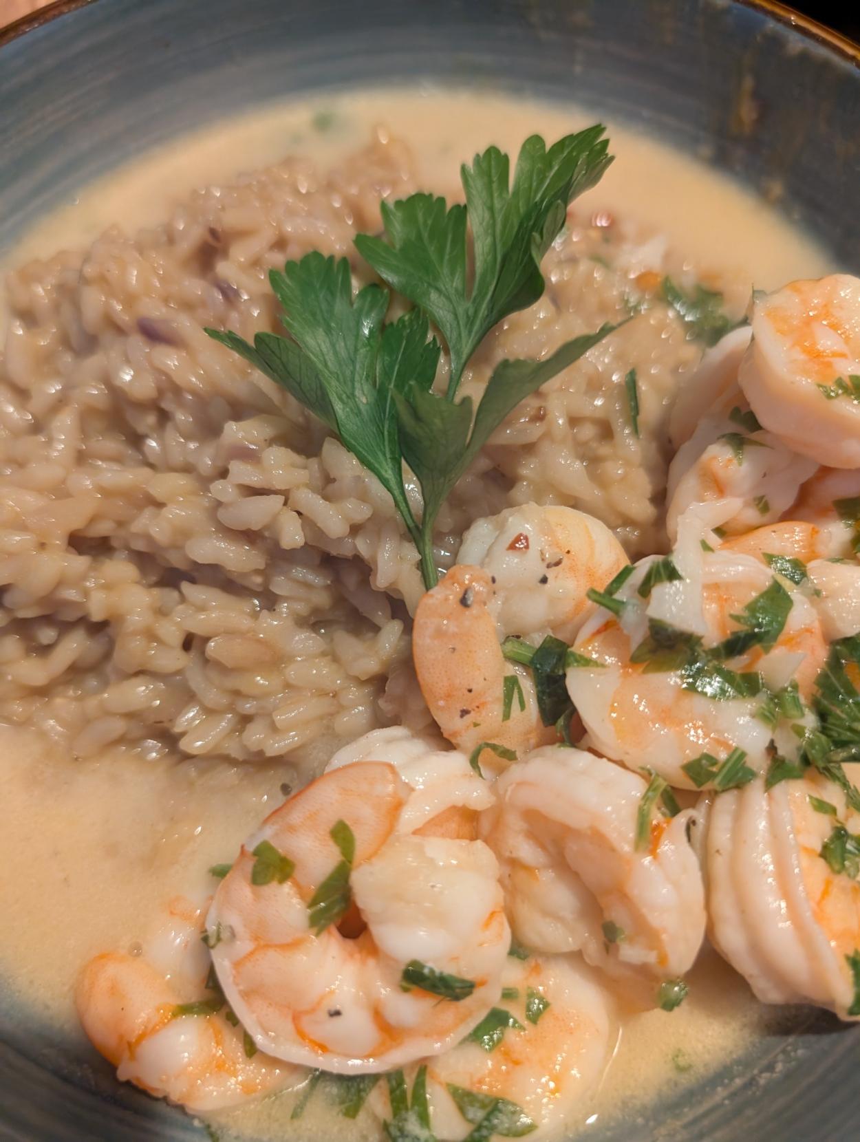 A bowl with a heap of risotto with shrimp scampi garnished with parsley