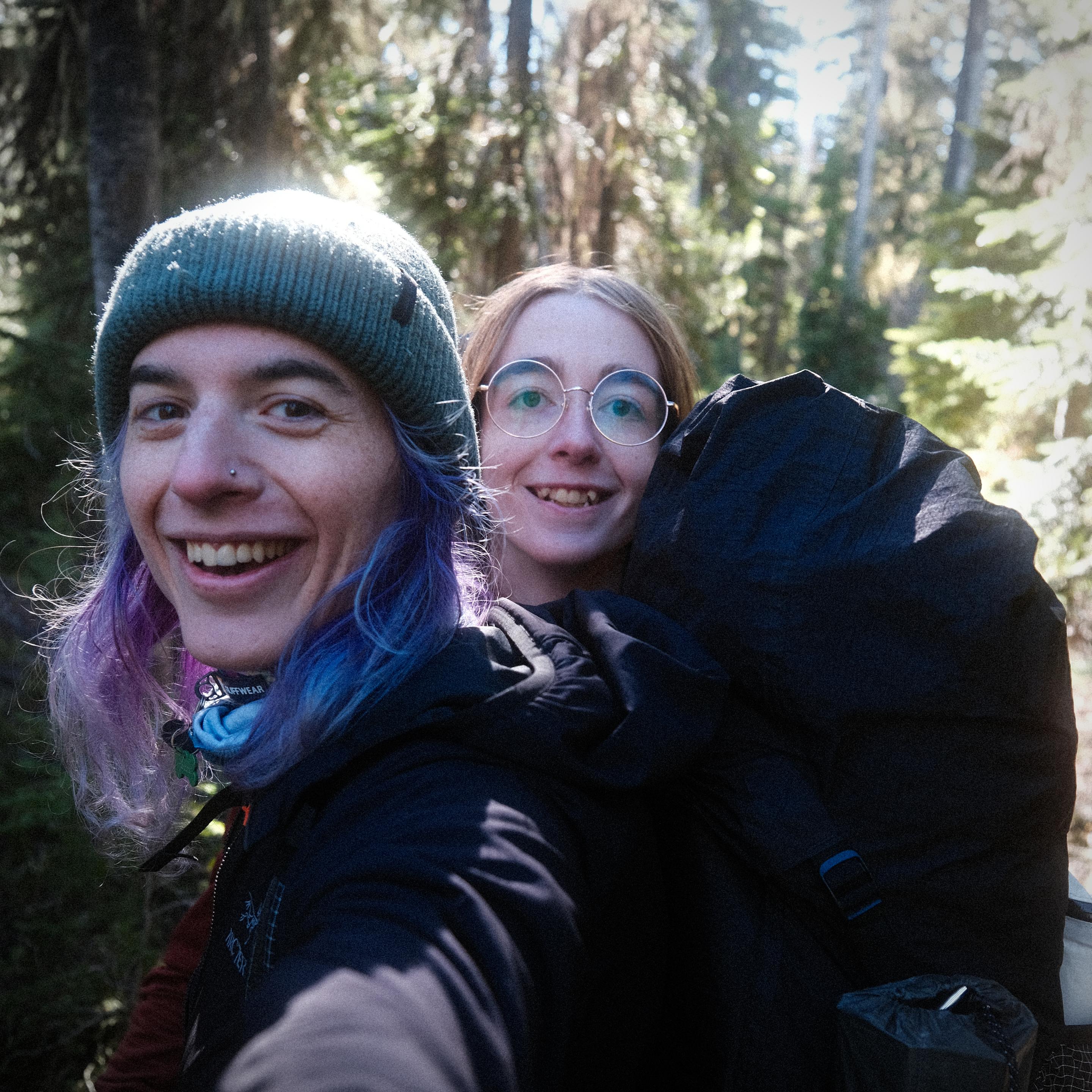 raven and natalie in a selfie while backpacking in a forest